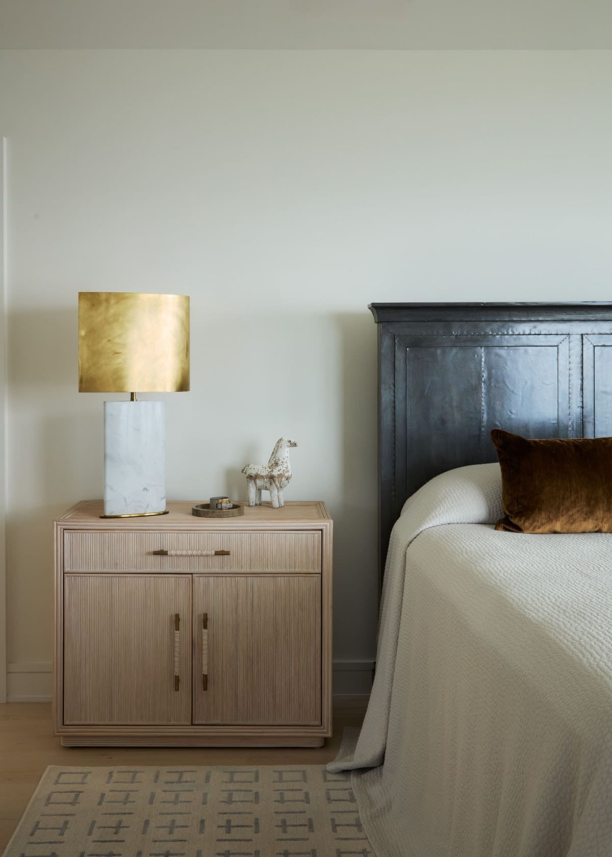 Bedroom nightstand with brass lamp and dark wood headboard