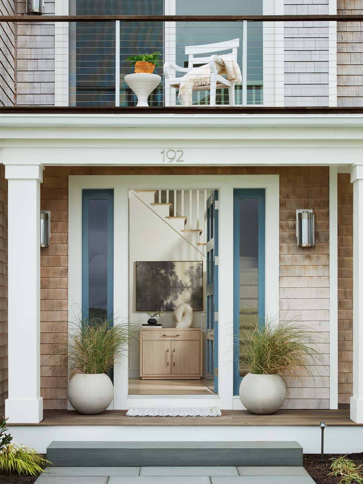 Coastal home entryway with blue front door and staircase view