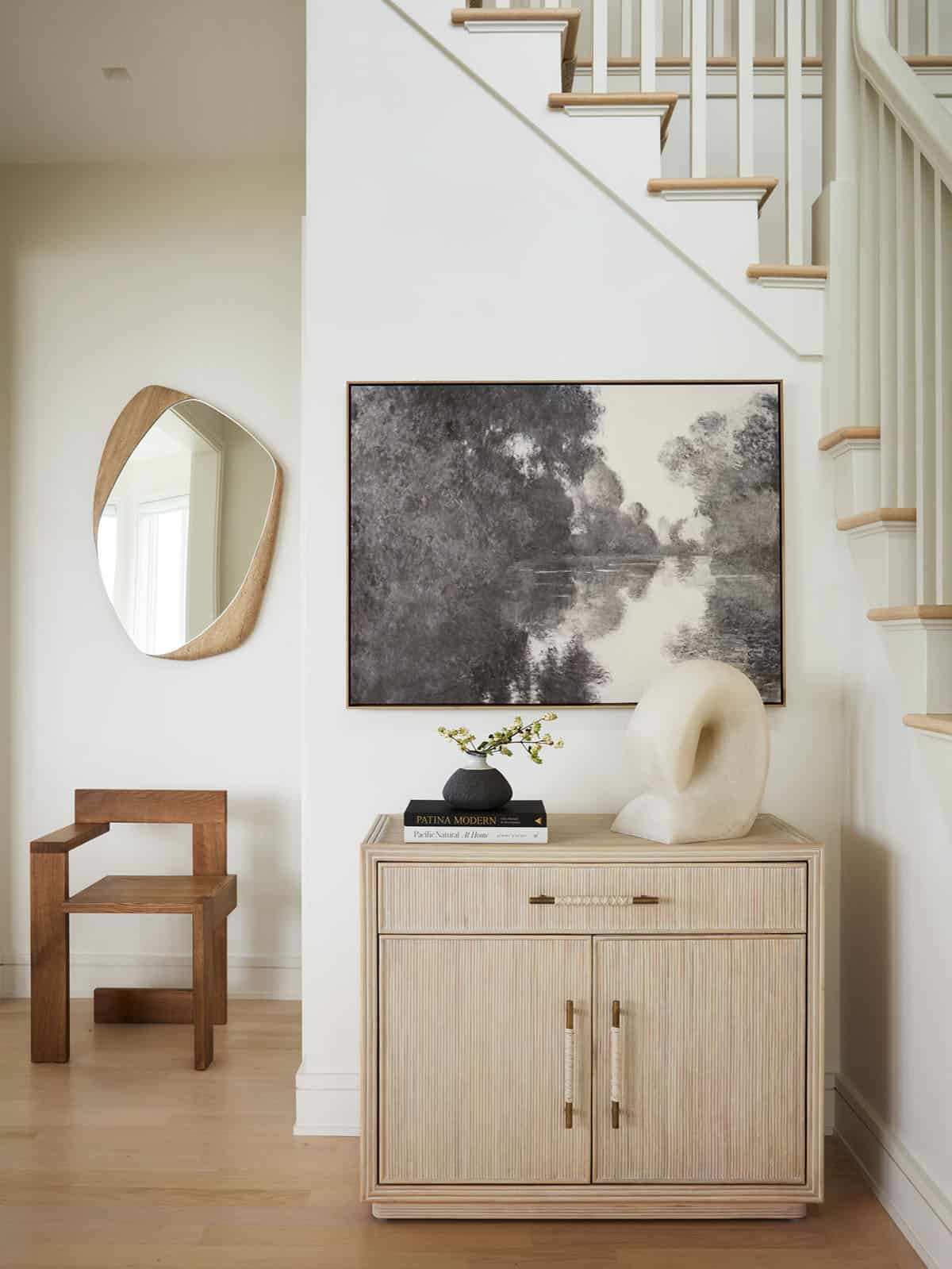 Foyer console table with abstract landscape art below staircase