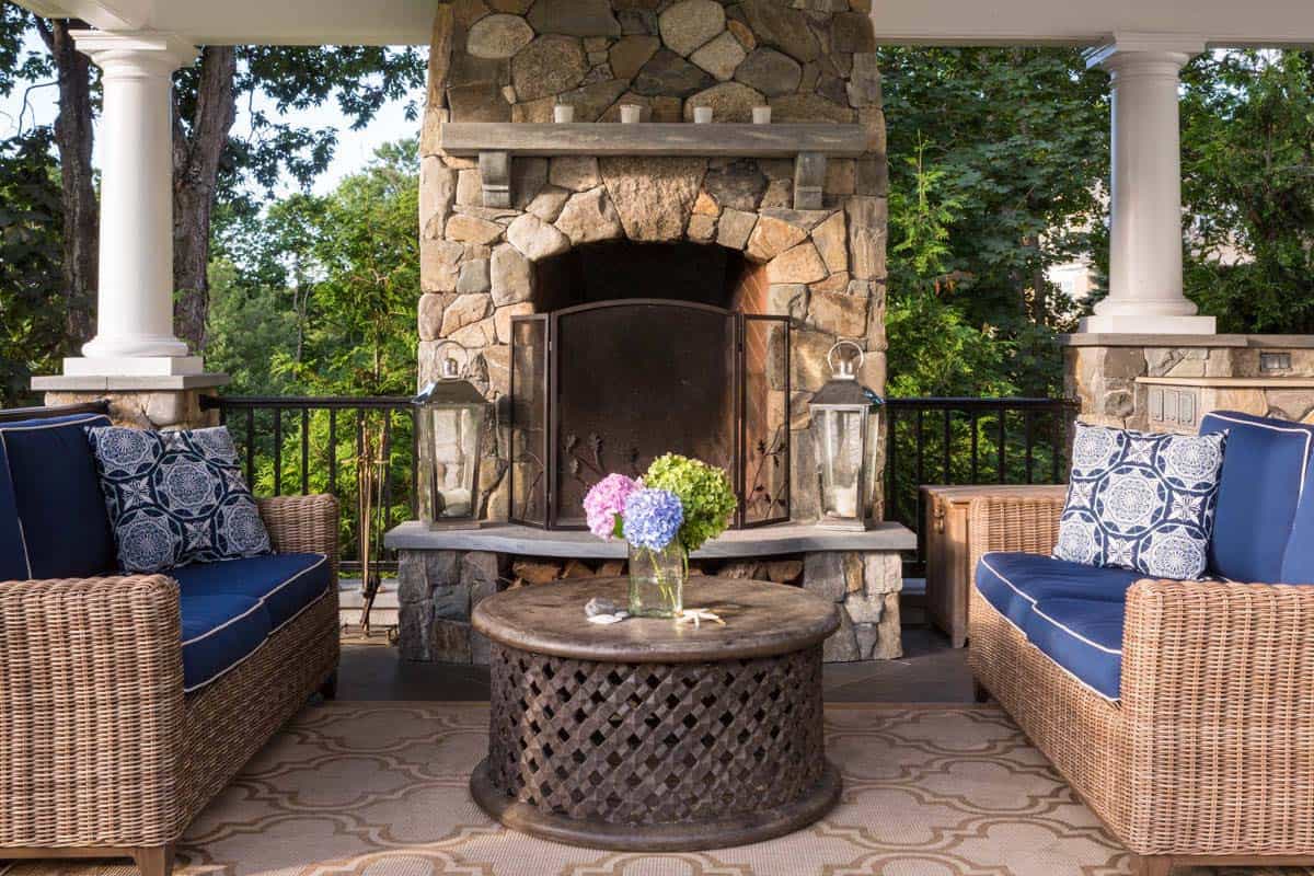 Fieldstone fireplace with wicker seating on a coastal covered porch