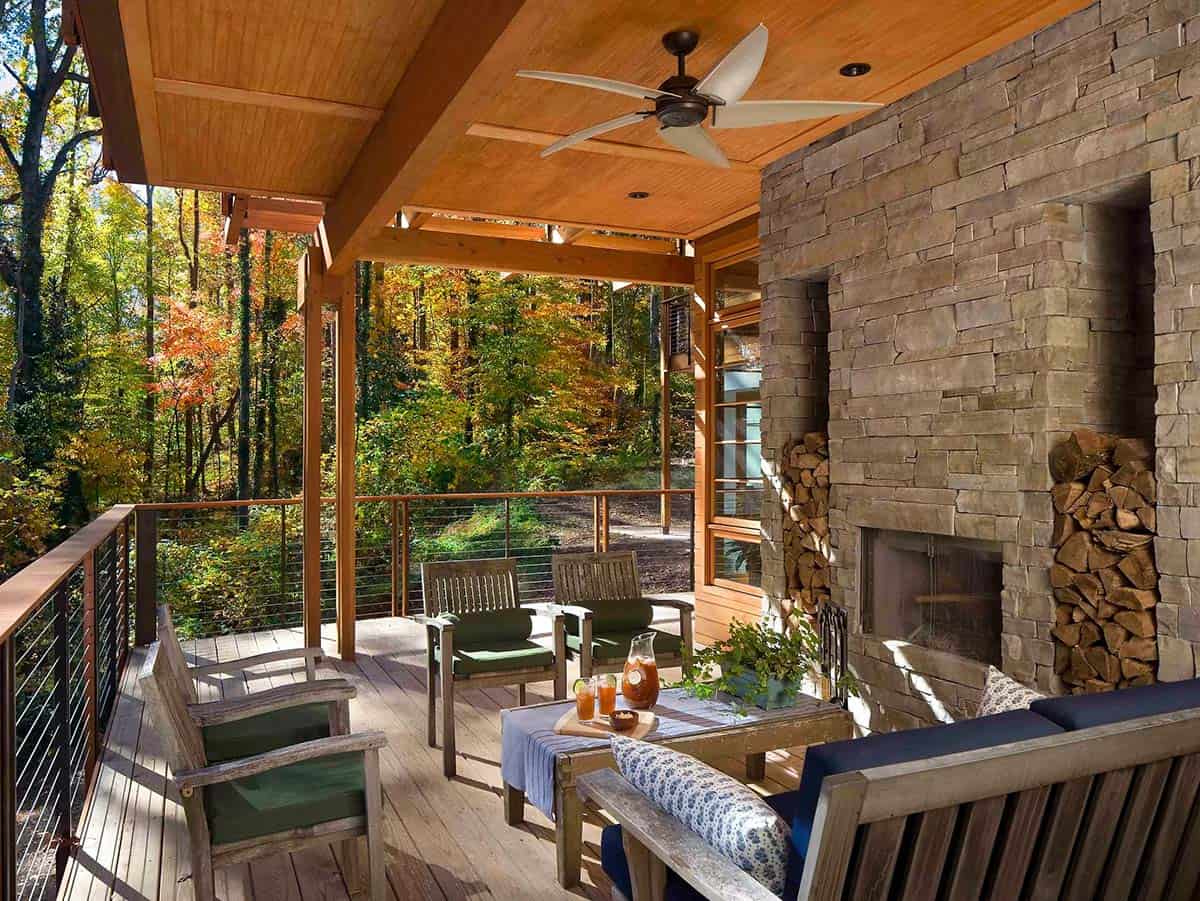 Stone fireplace with built-in firewood storage on a wooded outdoor deck