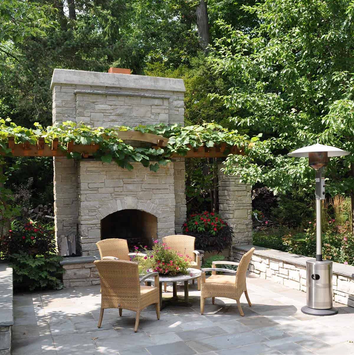 Stone fireplace with a grapevine-covered arbor on a stone patio