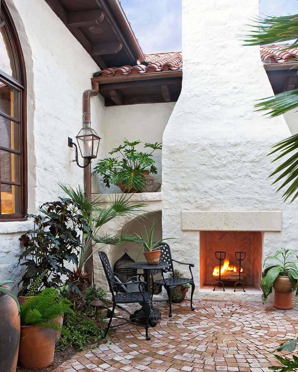 White stucco fireplace with herringbone brick on a Mediterranean-style patio