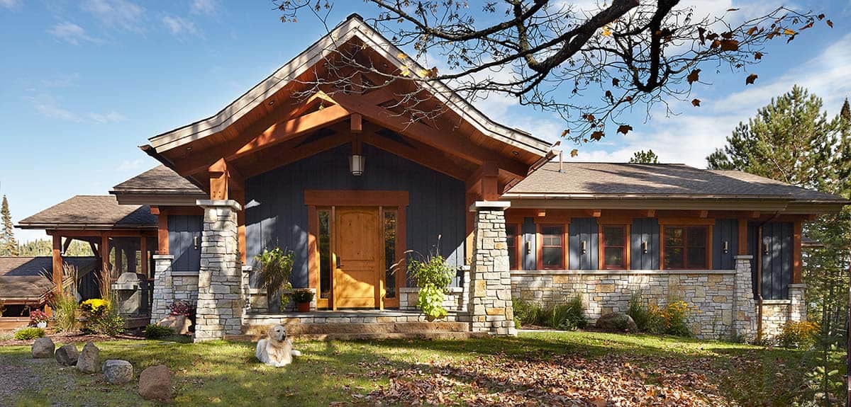 Timber-framed entrance with stone columns and golden retriever on lawn
