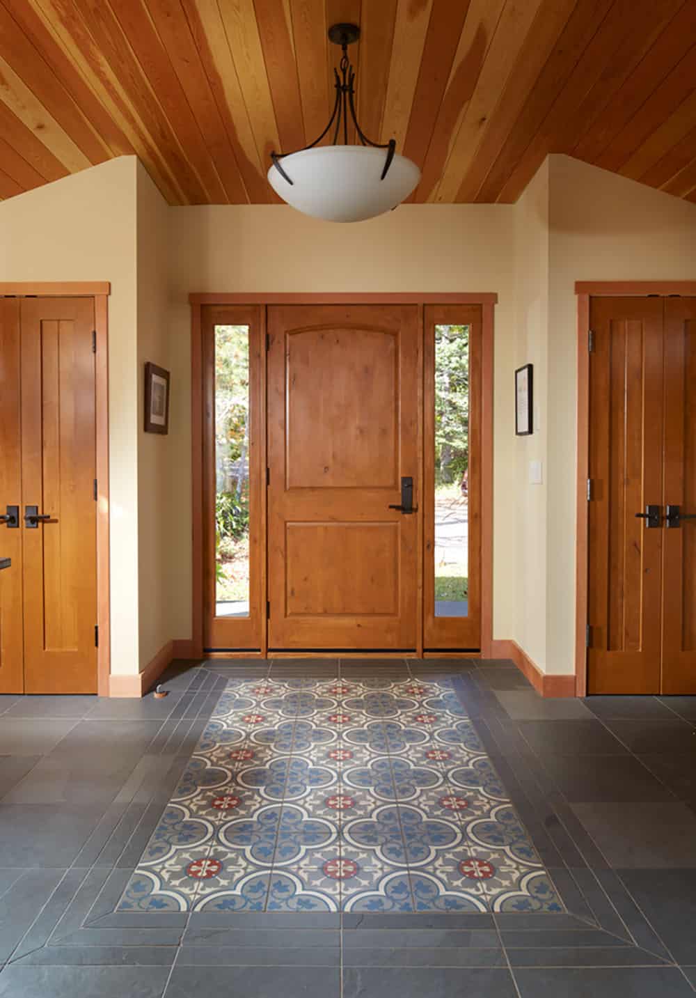Foyer with patterned tile rug, slate floor, and wood-paneled ceiling