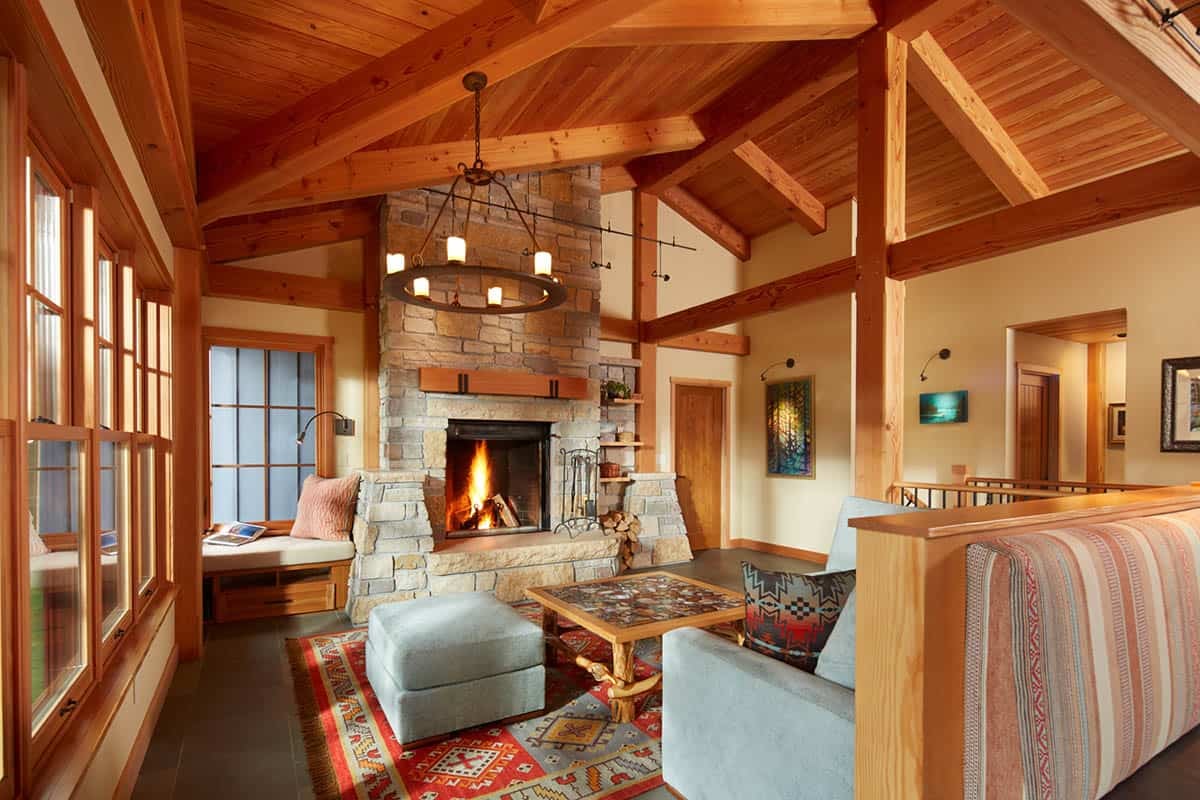 Vaulted living room with timber trusses, stone fireplace, and window seat