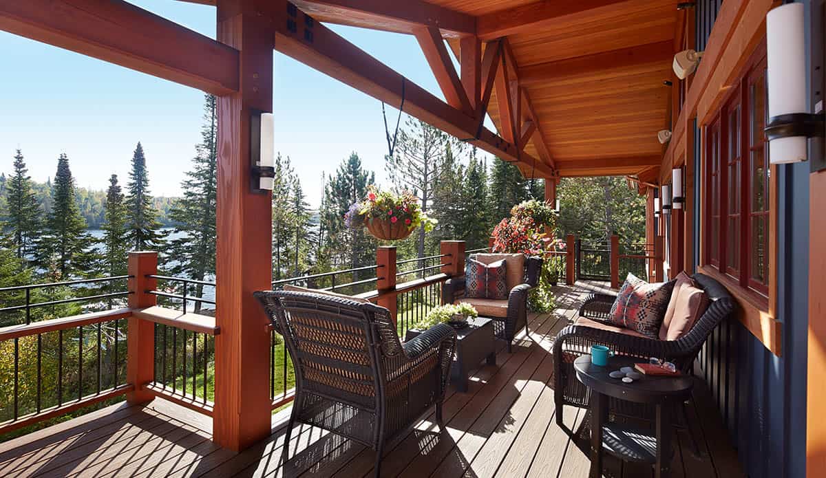 Covered deck with wicker furniture and timber-frame beams overlooking trees