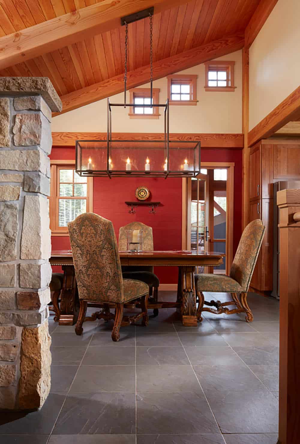 Dining room with red accent wall and upholstered antique-style chairs