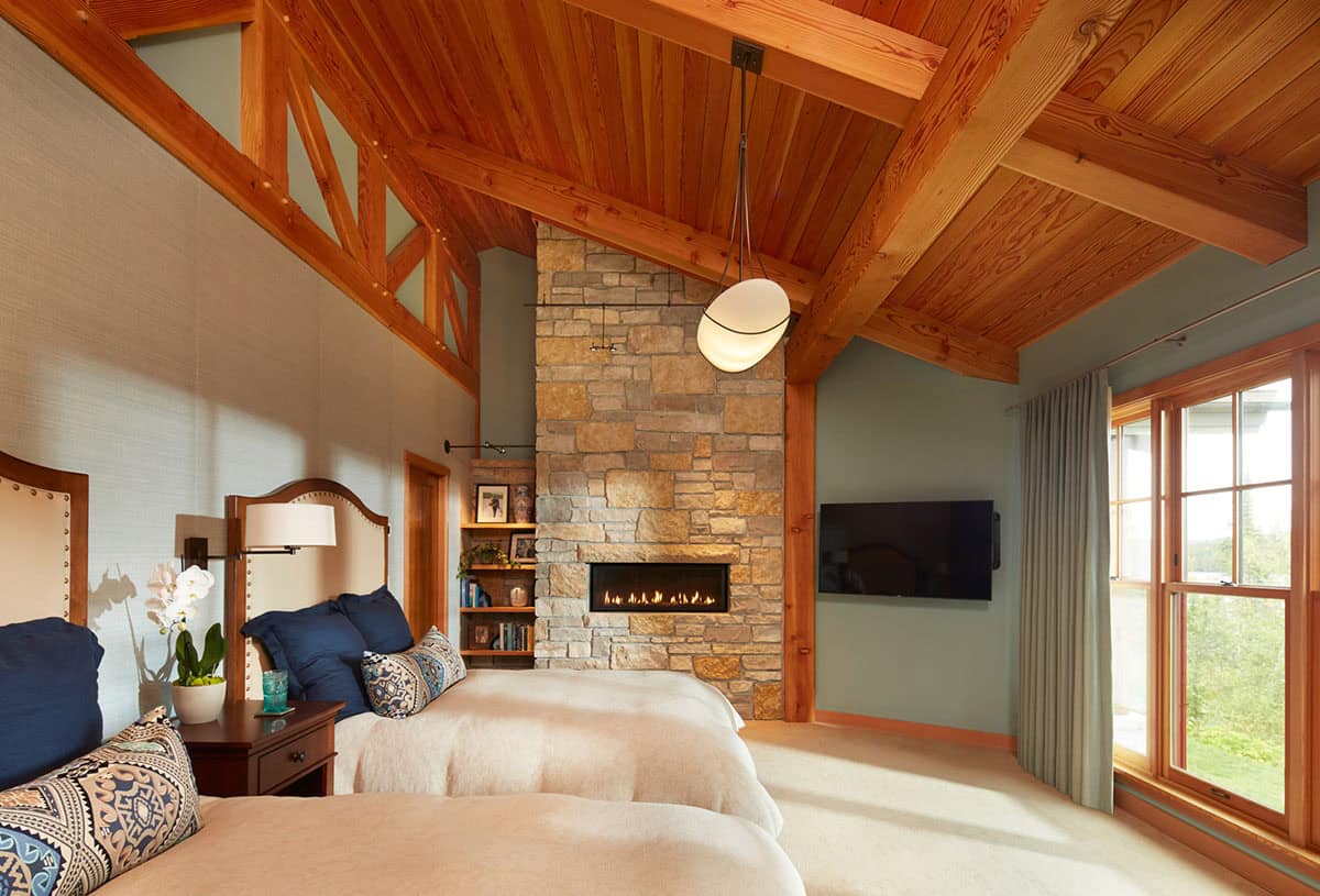 Bedroom with stone fireplace, exposed trusses, and twin beds