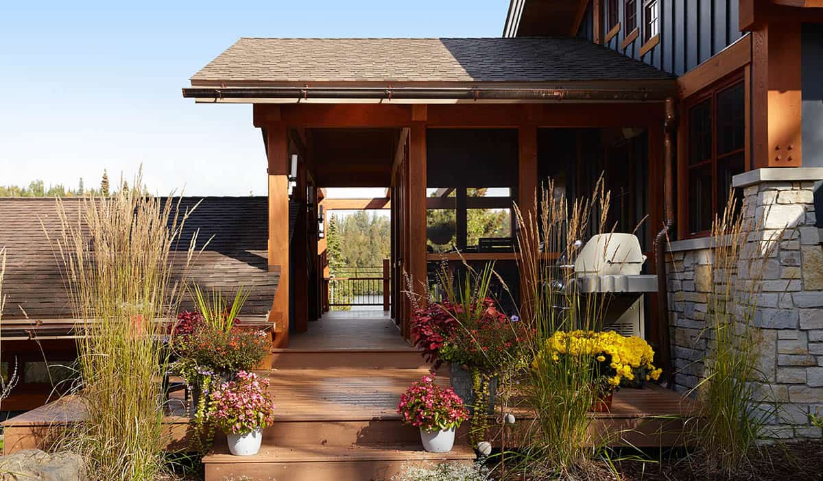 Covered walkway with stone column and potted flowers leading to porch