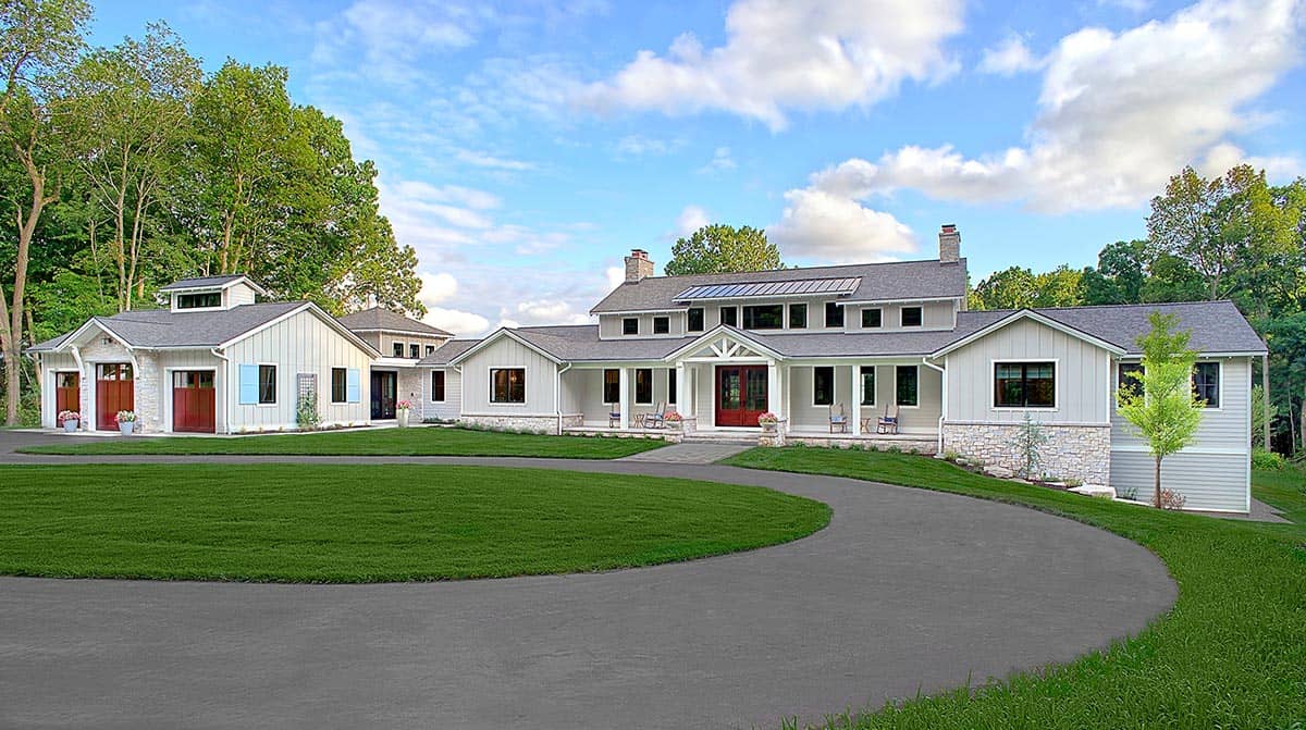 Exterior of a white farmhouse-style home with red doors, stone accents, and a circular driveway