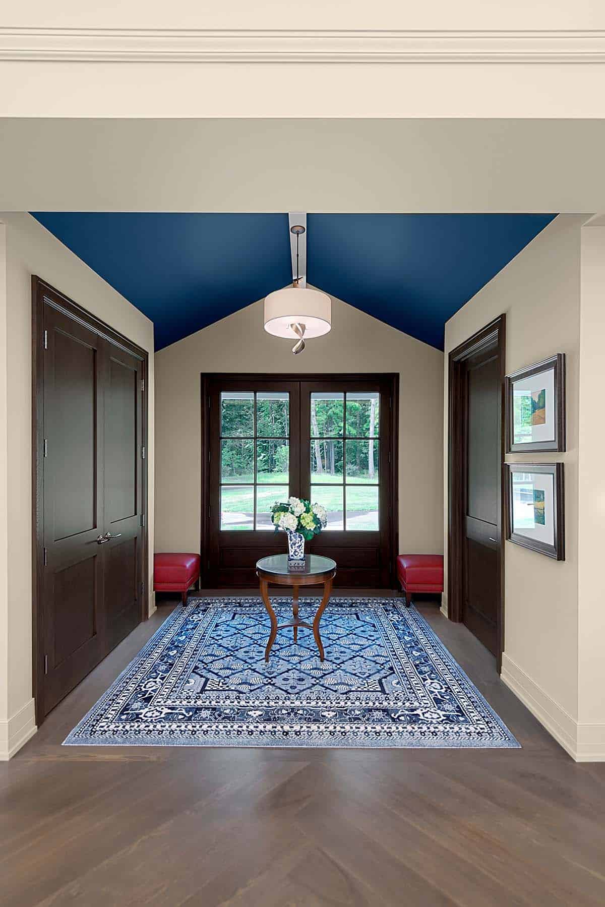 Entryway with navy vaulted ceiling, dark wood doors, and a blue patterned area rug