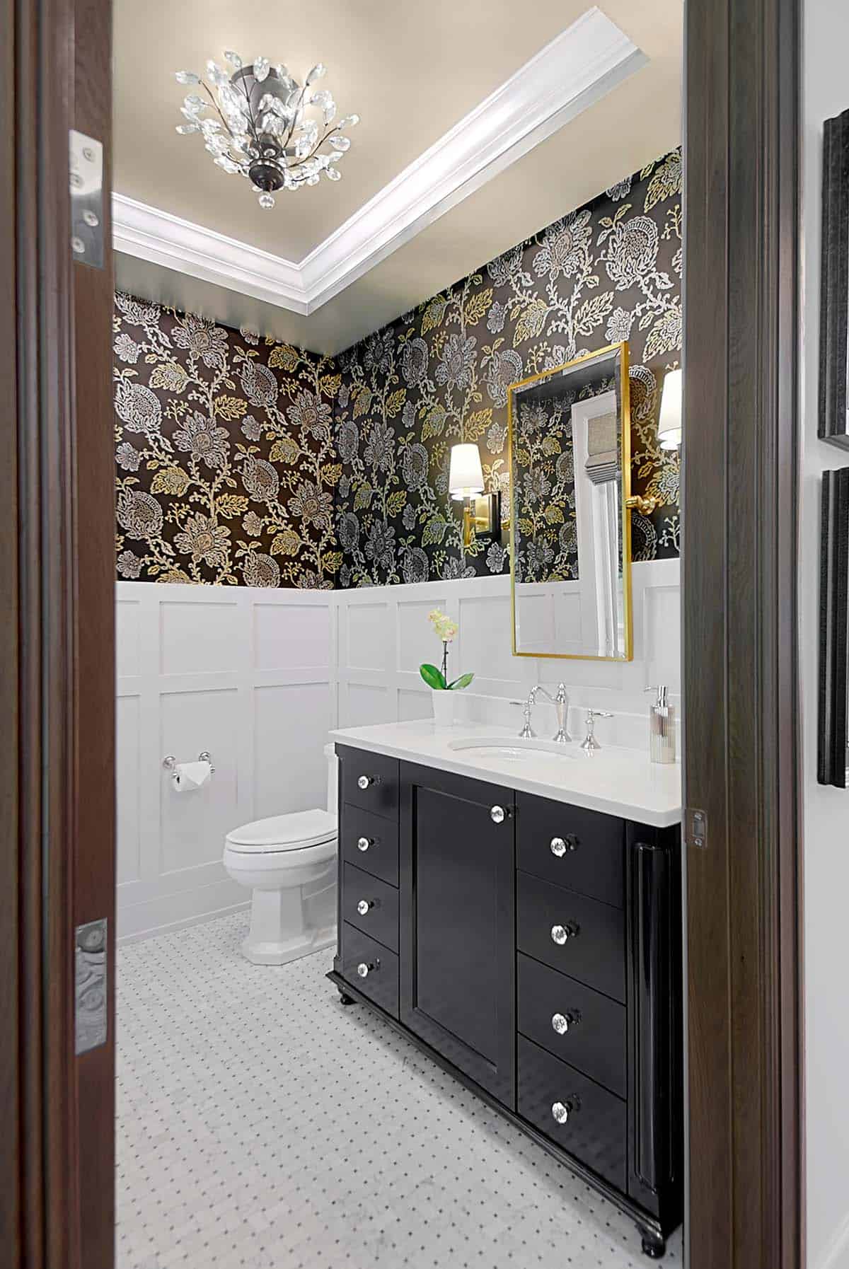 Powder room with black-and-gold floral wallpaper and a black vanity with crystal knobs
