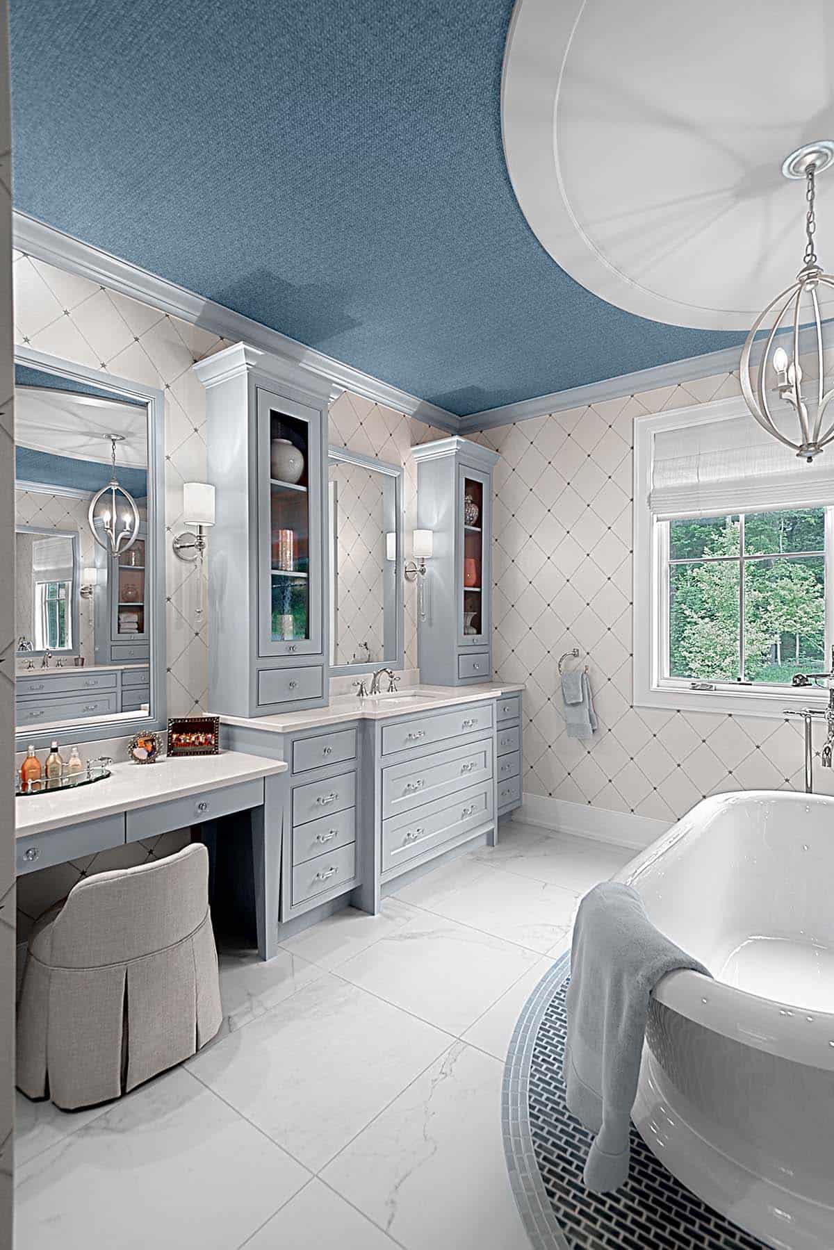 Primary bathroom vanity area with light blue cabinetry and a makeup desk