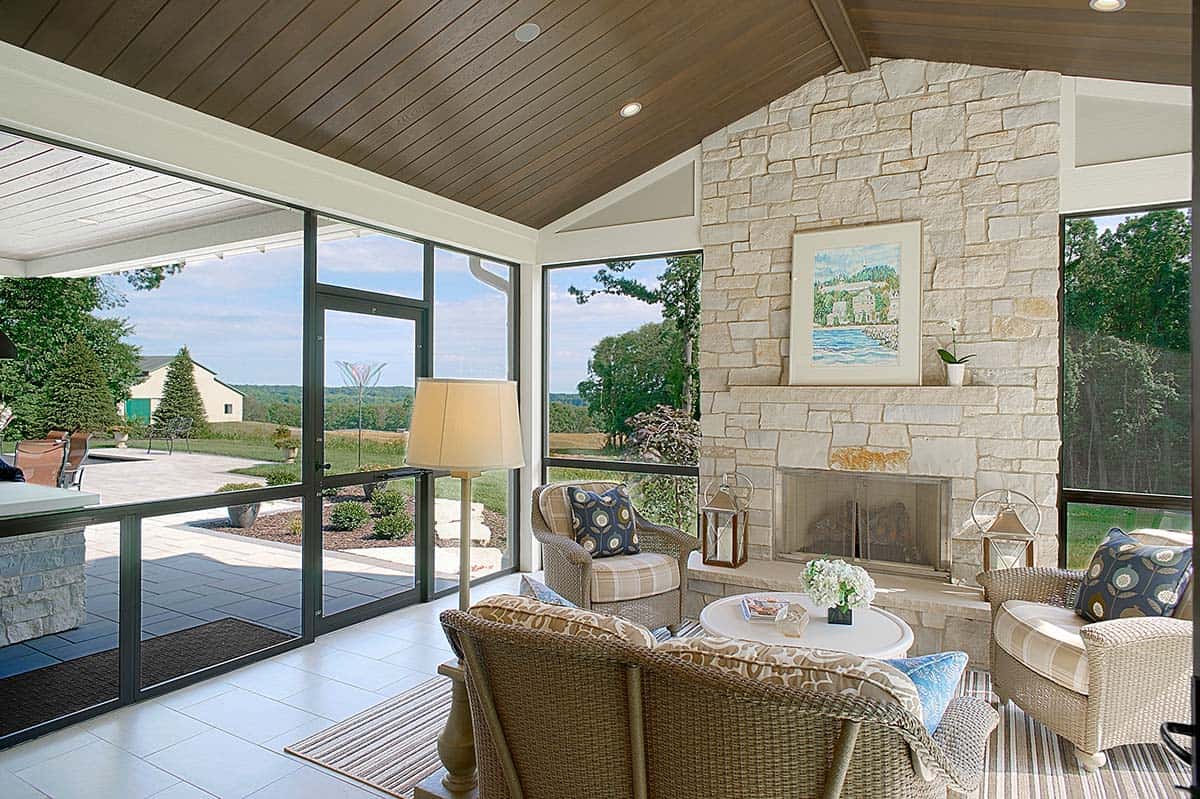 Screened porch with wicker furniture and a stone fireplace overlooking the yard