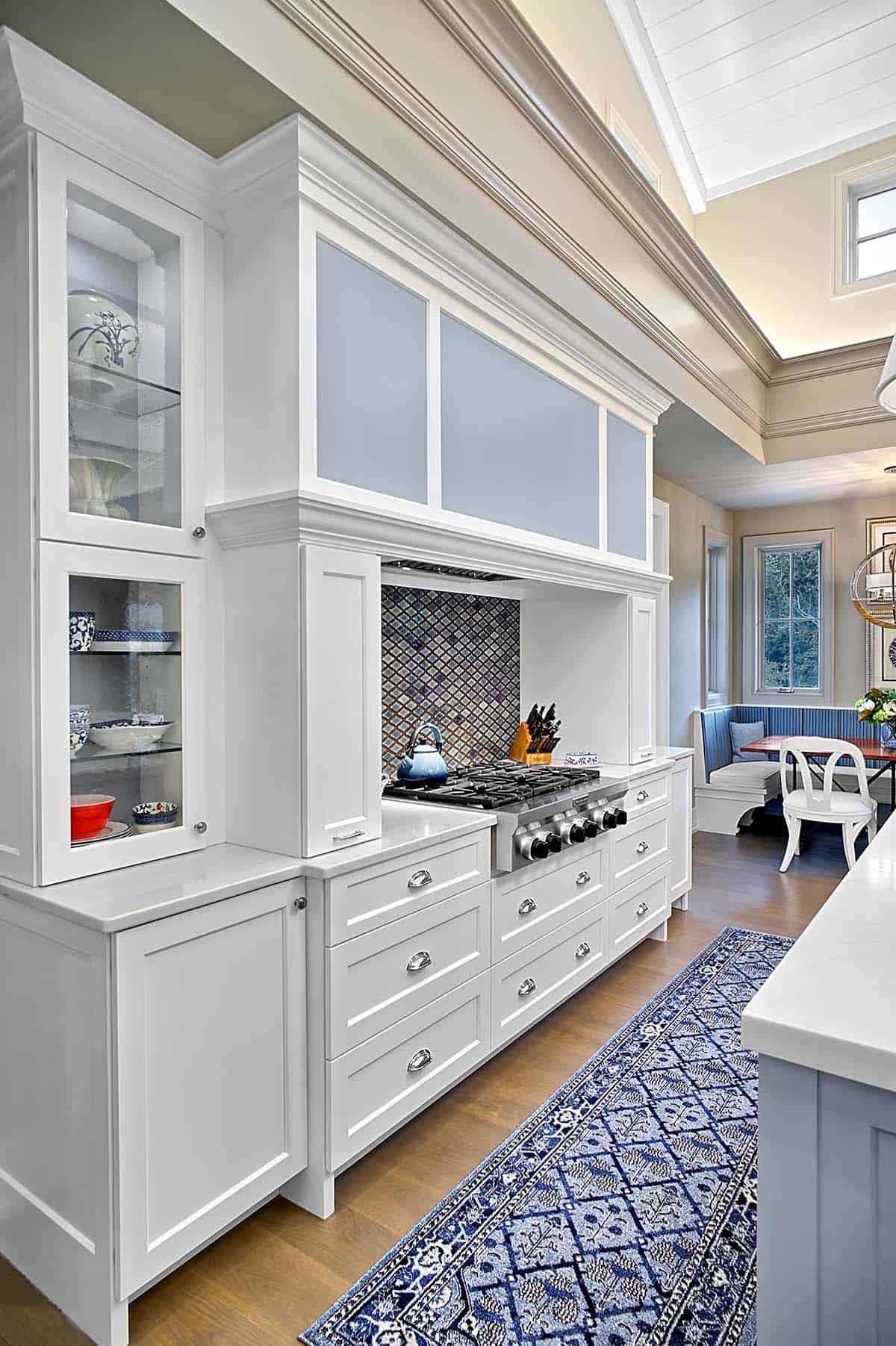 Detailed view of white kitchen cabinetry, range, and glass-front hutch