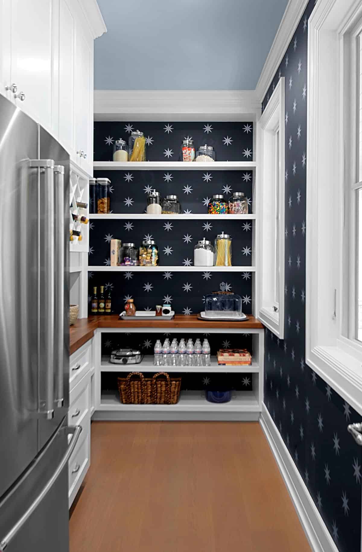 Walk-in pantry with navy star-print wallpaper and open shelving