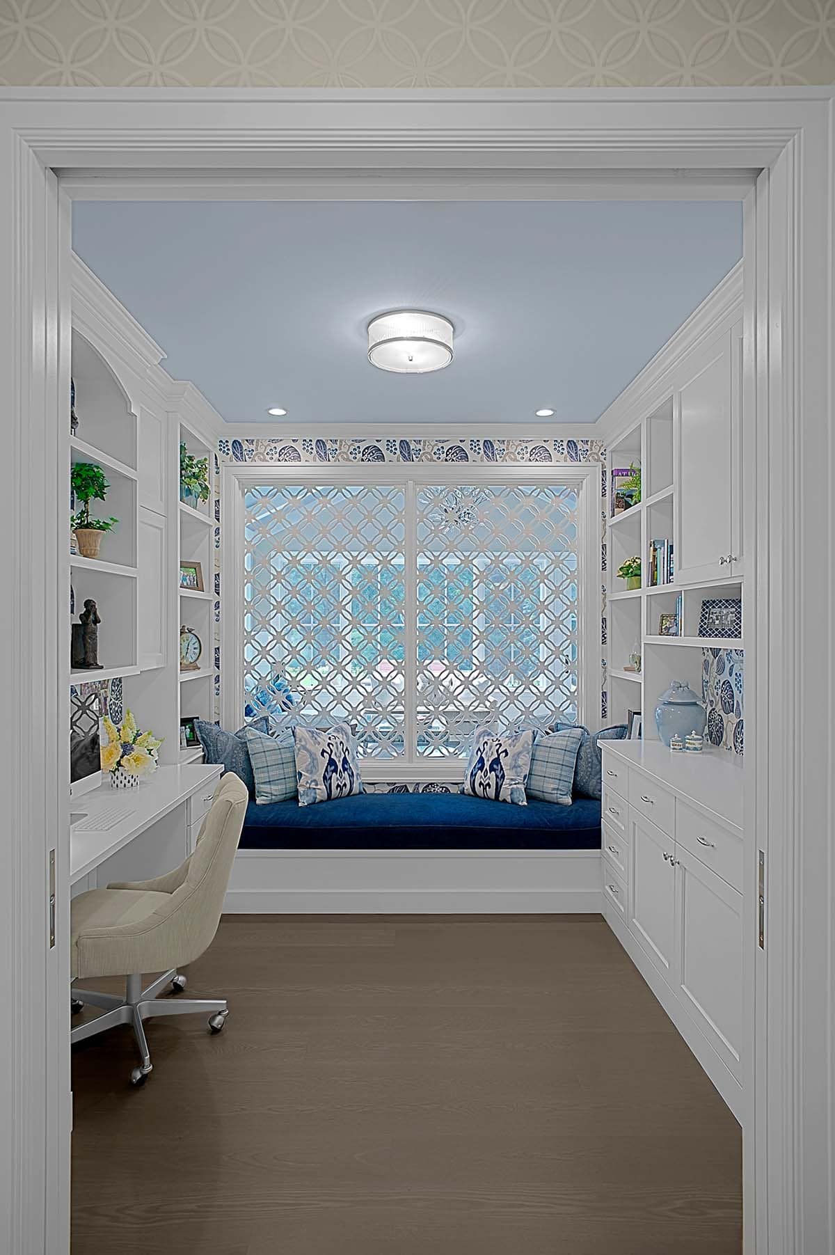 Home office nook with a patterned lattice window and blue built-in window seat