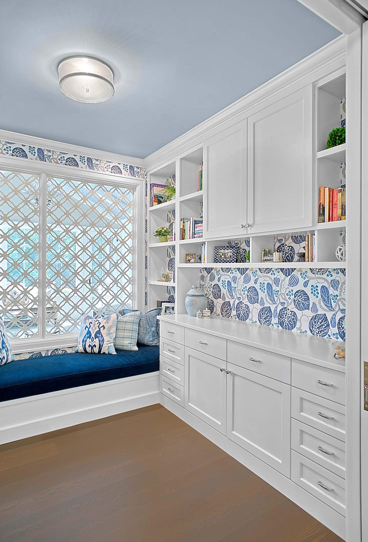 Home office shelving with blue floral wallpaper and open bookcases