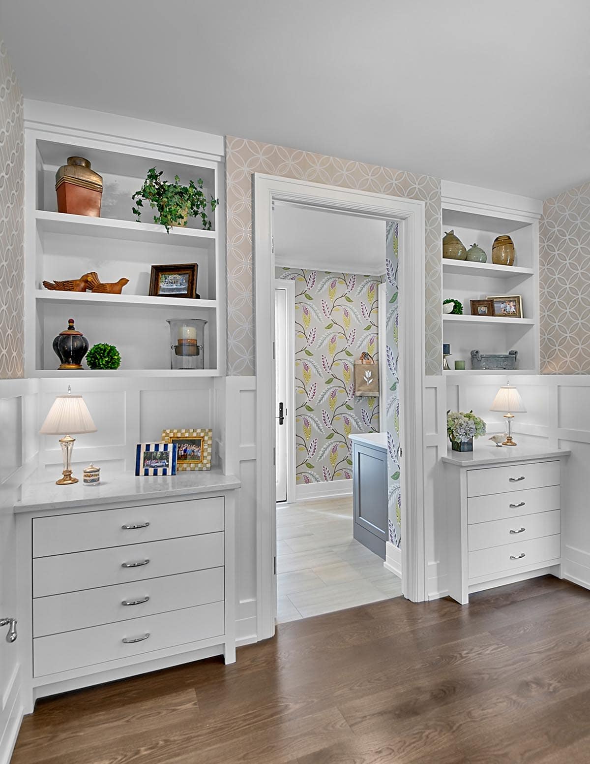 Bedroom built-ins flanking a doorway into a wallpapered hallway