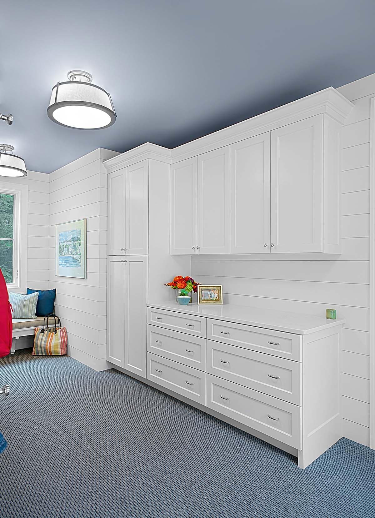 Mudroom storage wall with white cabinetry and shiplap paneling