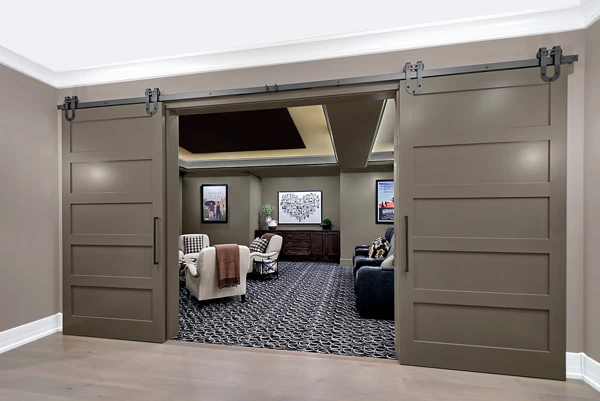 Sliding barn doors opening to a media room with patterned carpet