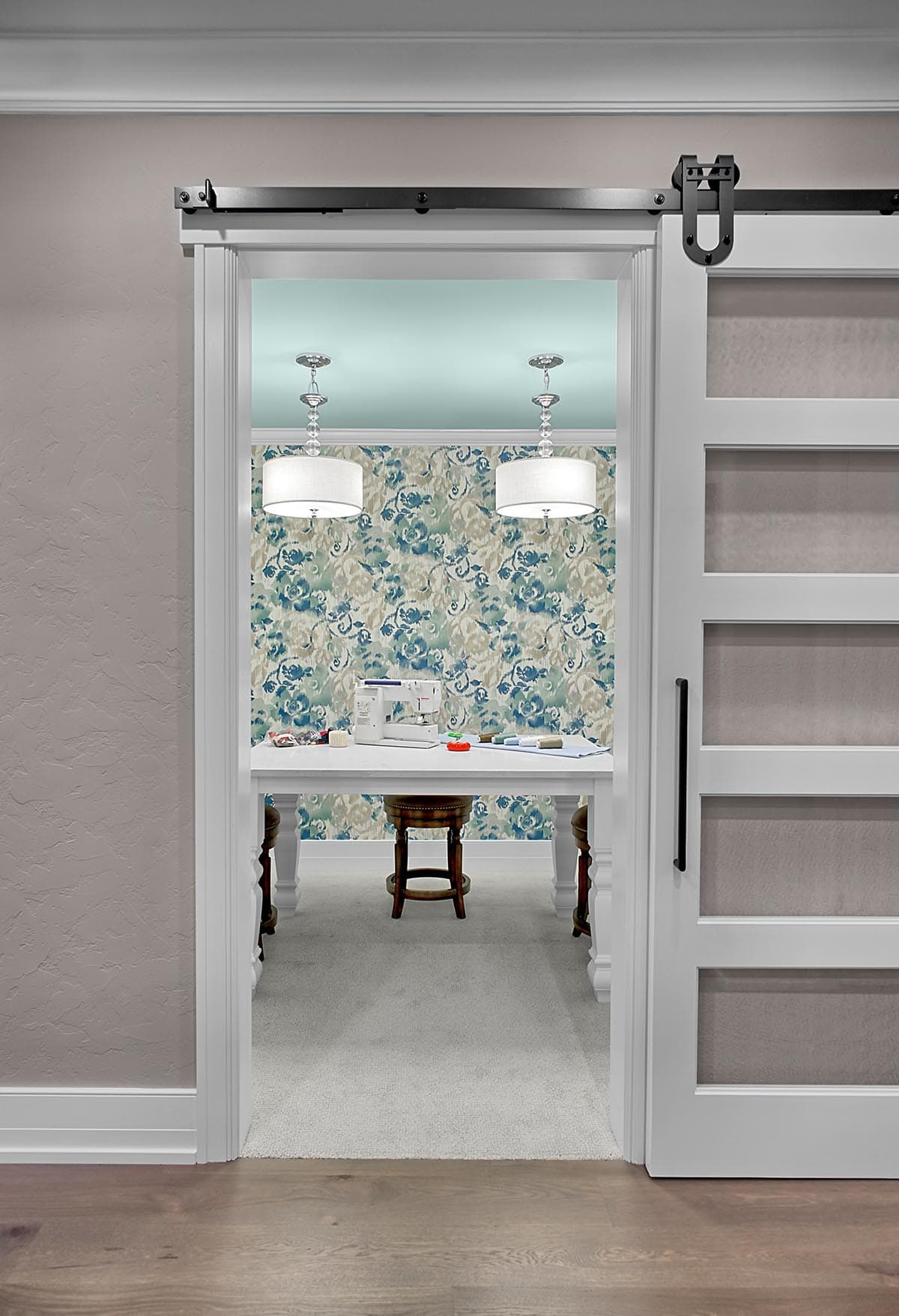 Barn door opening into a craft room with blue floral wallpaper