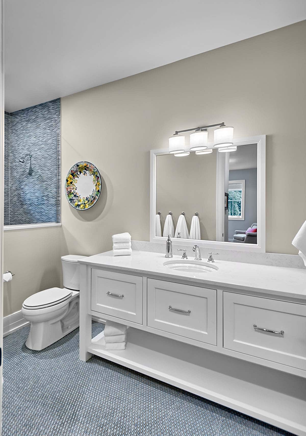 Bathroom vanity with white cabinetry and a mosaic-tiled shower