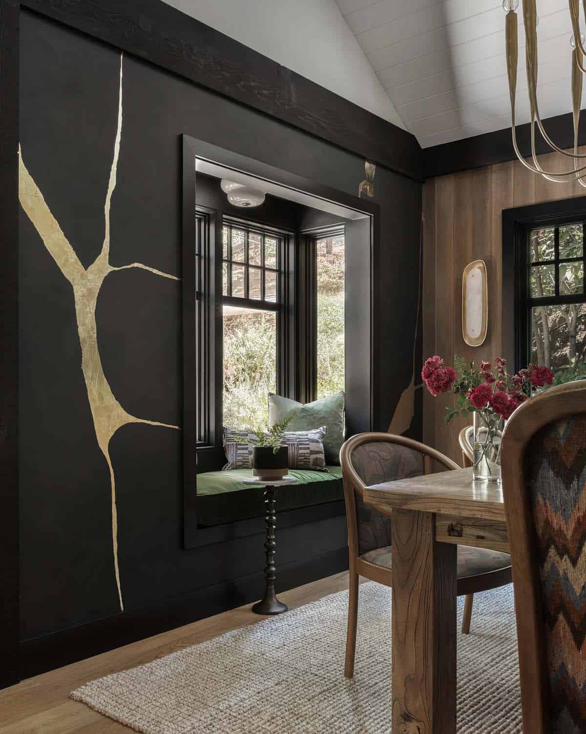 Dark moody dining nook with gold tree mural and green velvet window seat
