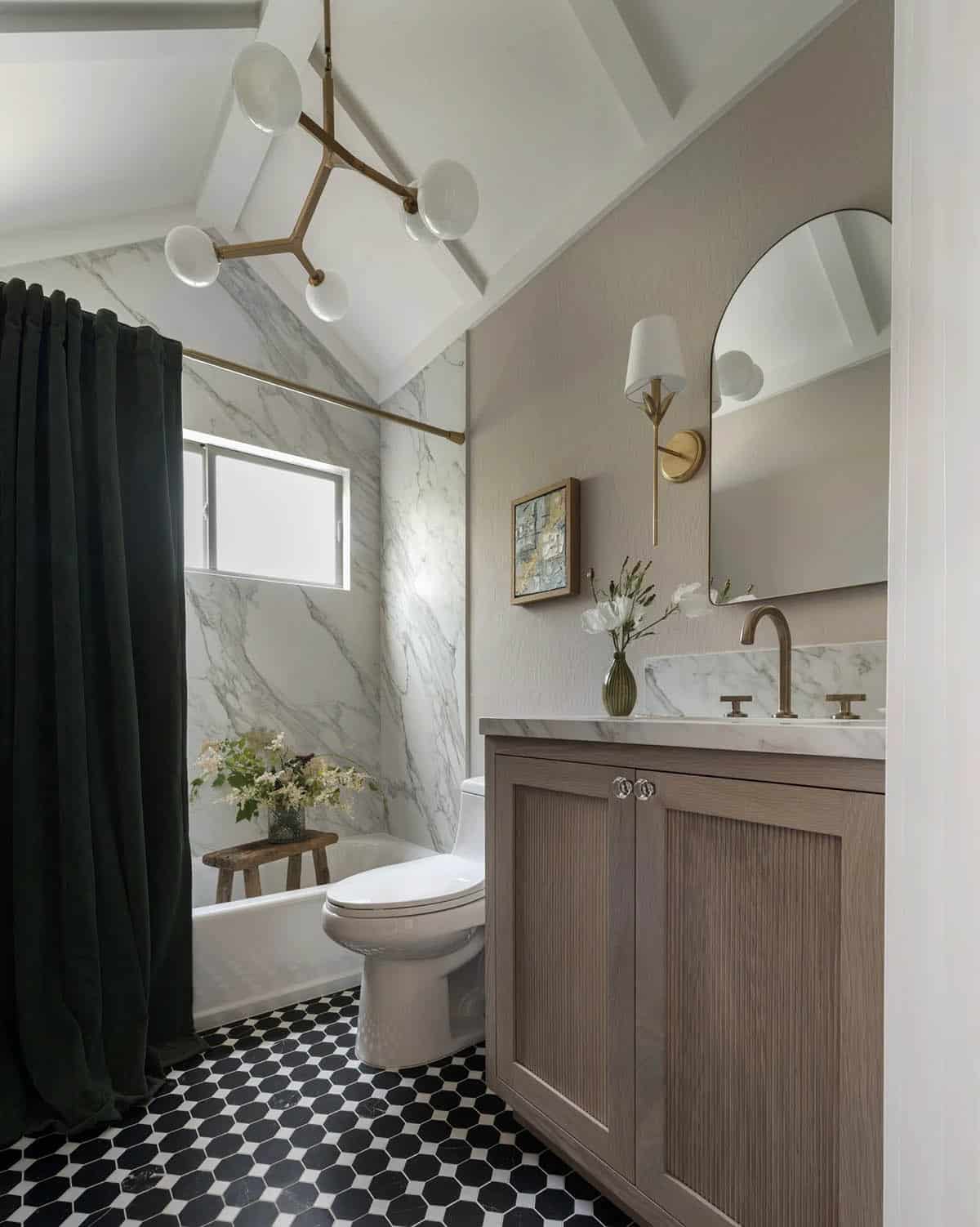 Bathroom with arched mirror, marble tile shower, dark green curtain, and wood vanity