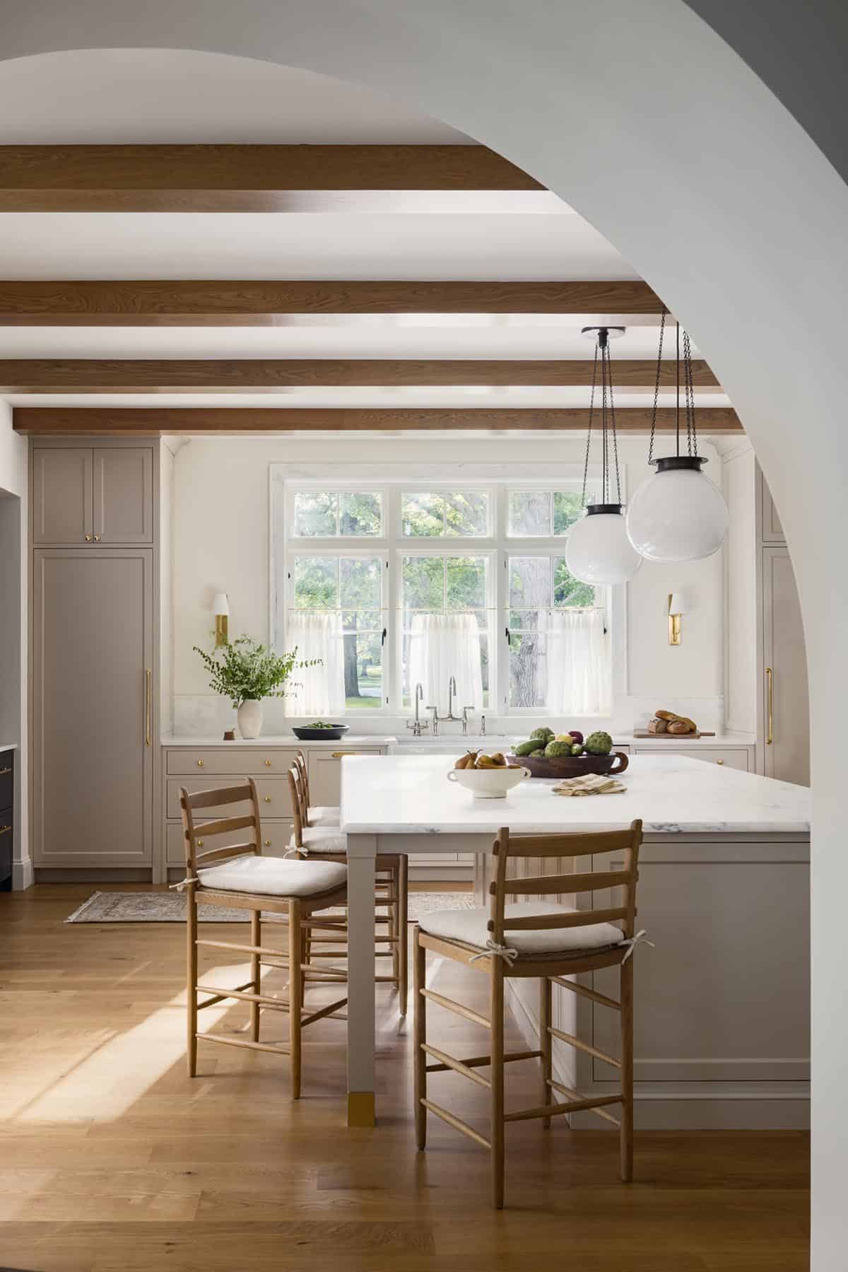 Kitchen island with wood counter stools, globe pendant lights, and wood ceiling beams