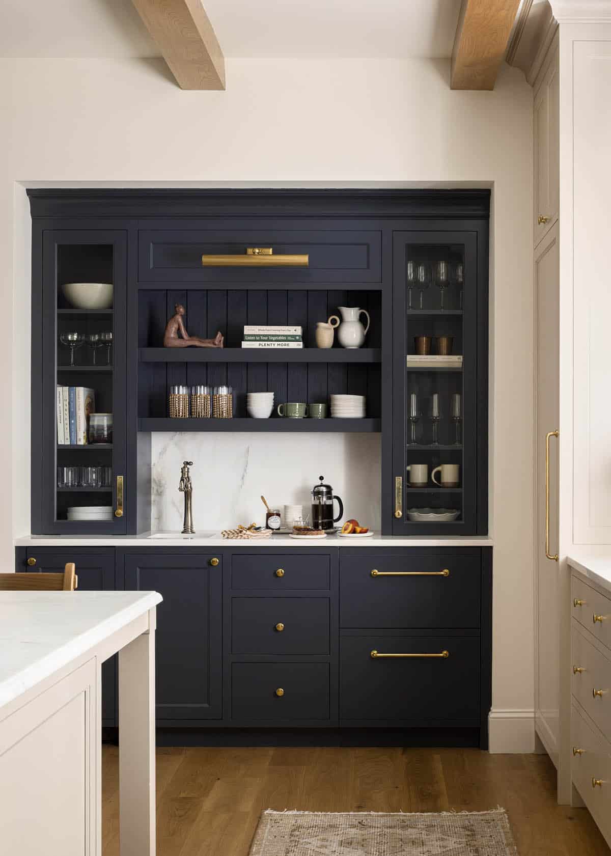 Navy blue butler's pantry with glass cabinets, brass hardware, and marble backsplash