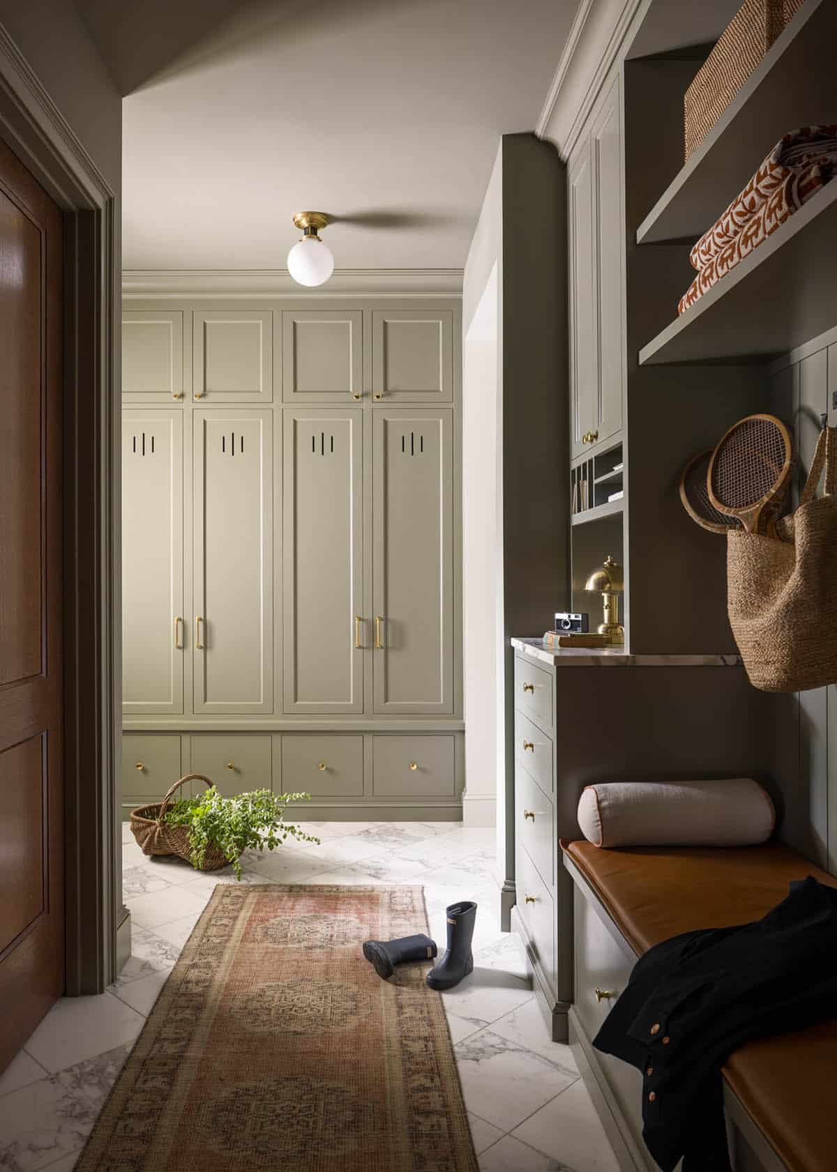 Mudroom with sage green lockers, leather bench, marble floor, and vintage runner rug