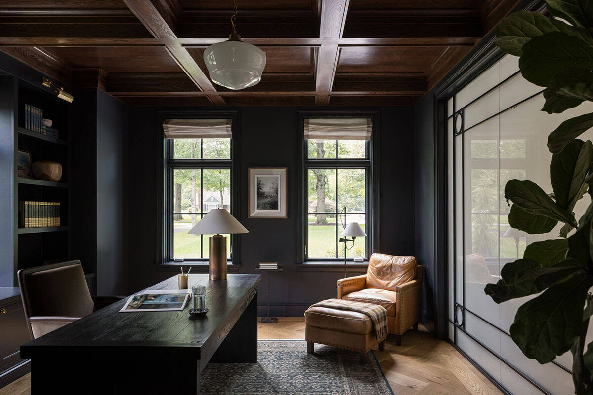 Dark wood-paneled home office with coffered ceiling, leather chair, and desk