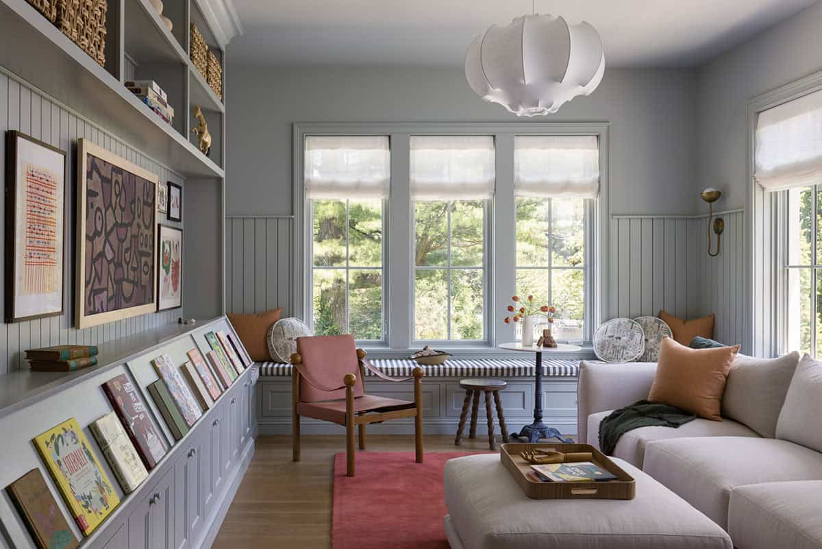 Gray-toned playroom with window seat, built-in bookshelves, and colorful artwork