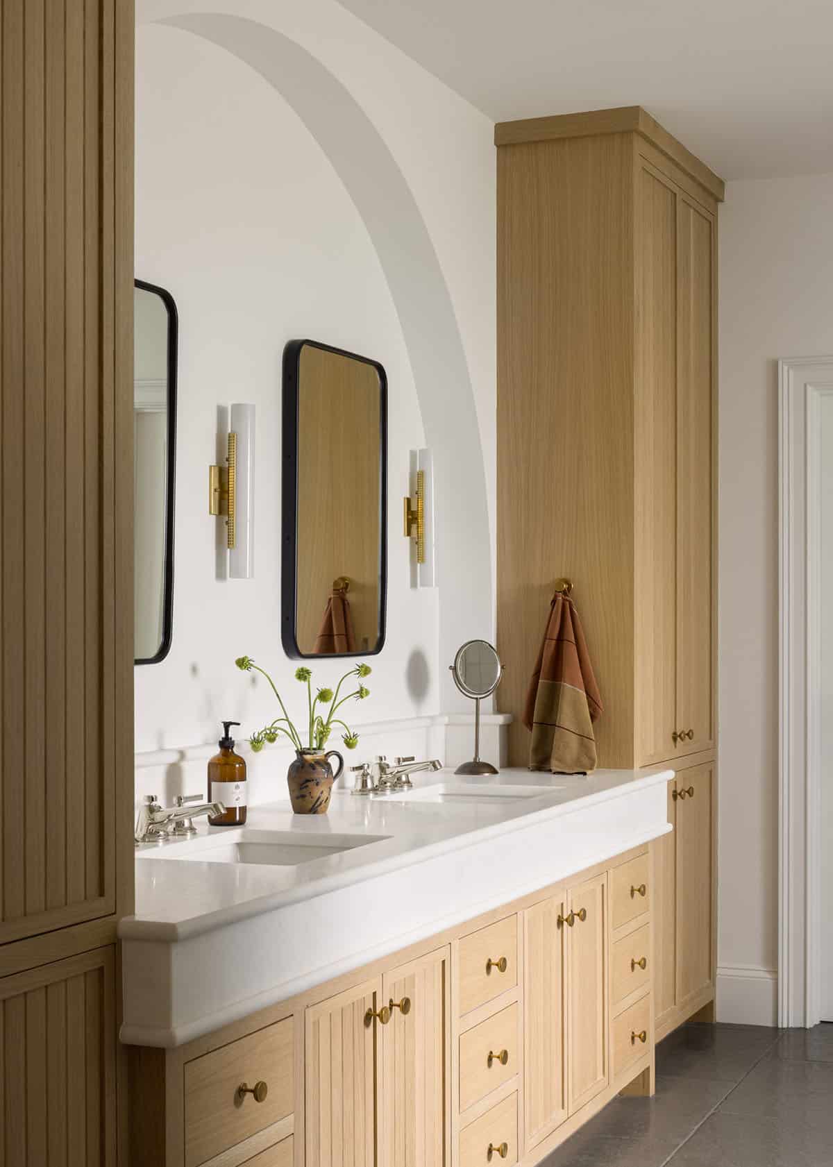 Bathroom double vanity with white oak cabinetry and arched mirror niche