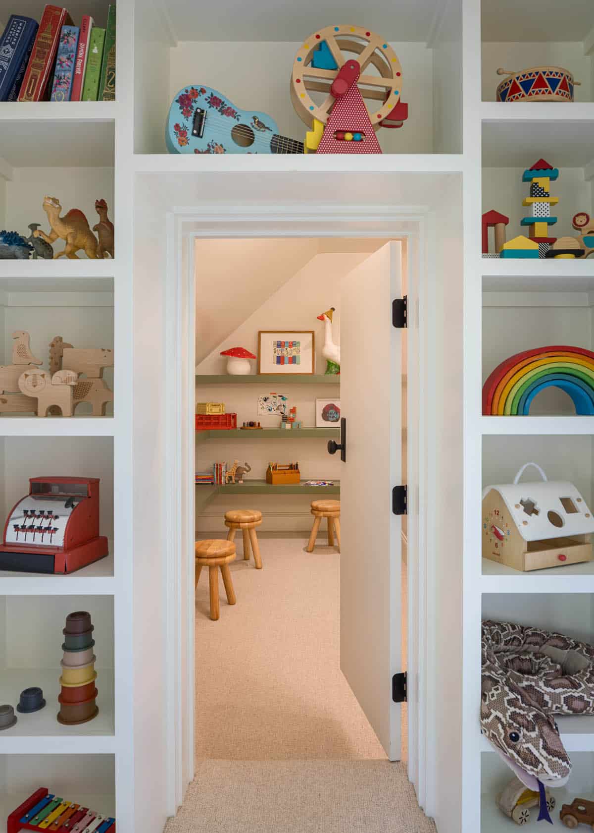 Colorful children's playroom nook viewed through doorway with toy-filled shelving