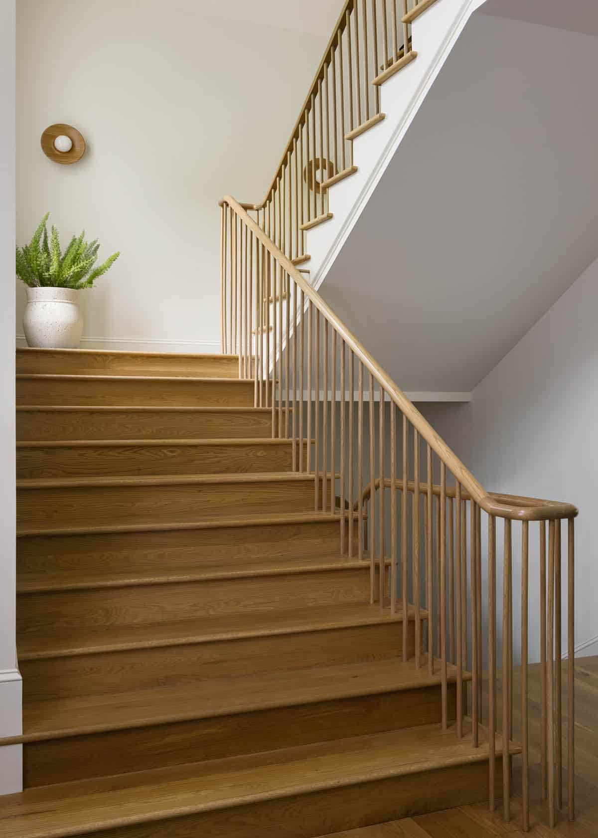 Oak staircase with slatted railing and potted fern on landing
