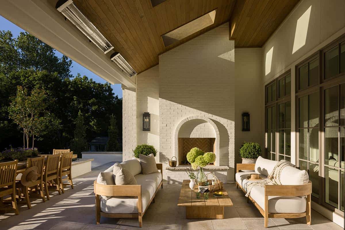 Covered patio with white sofas, outdoor fireplace, and vaulted wood ceiling