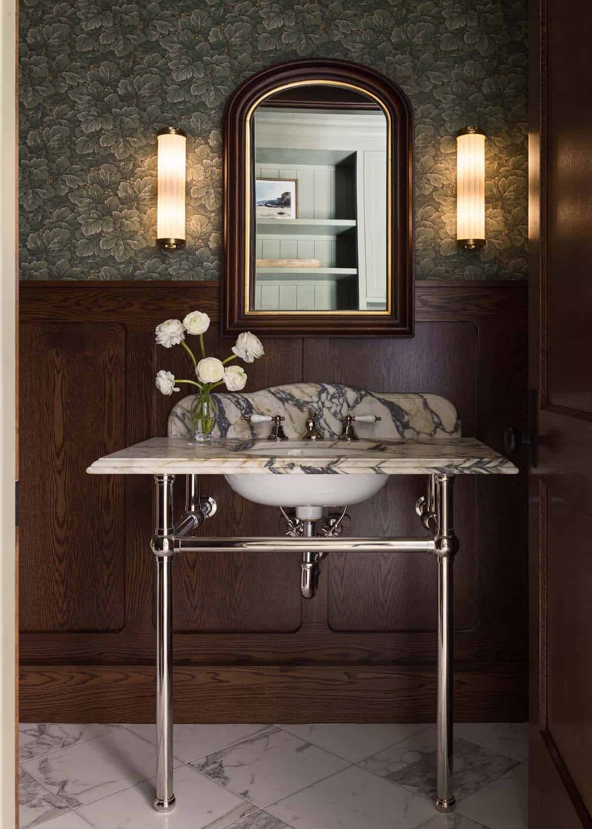 Dark wood-paneled powder room with floral wallpaper and marble console sink