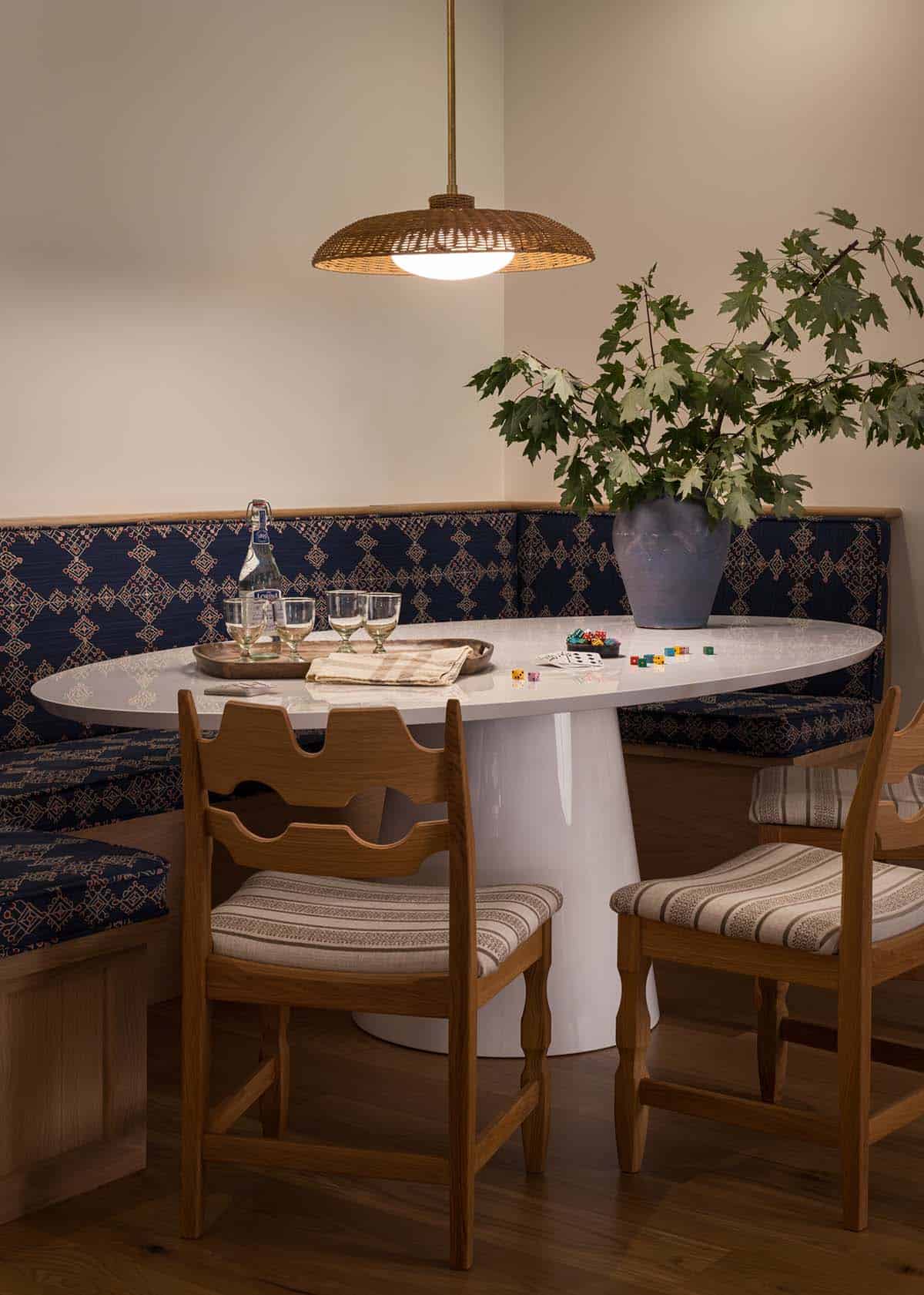 Breakfast nook with oval white table, patterned banquette, and woven pendant light