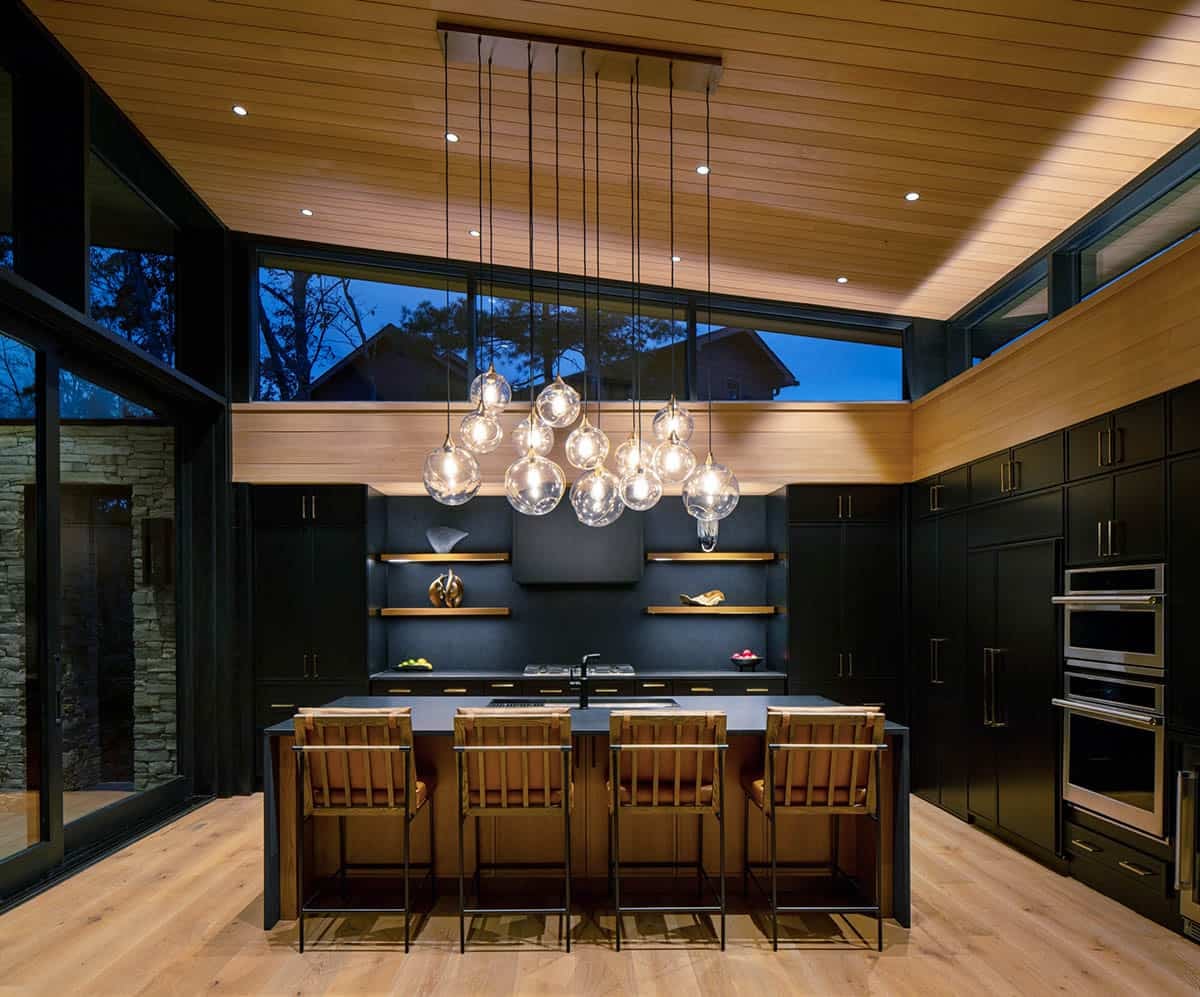 Kitchen island with leather stools lit by glass bubble chandelier at night
