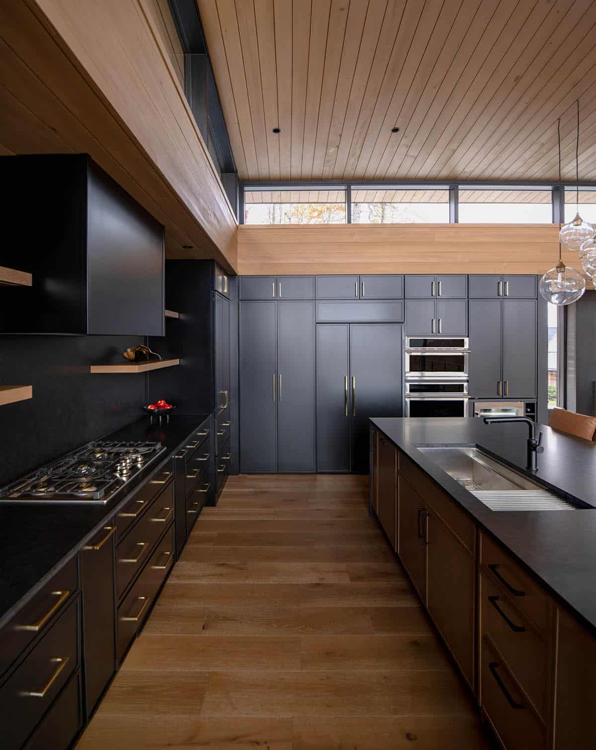 Galley kitchen with black cabinets, brass hardware, and wood plank ceiling