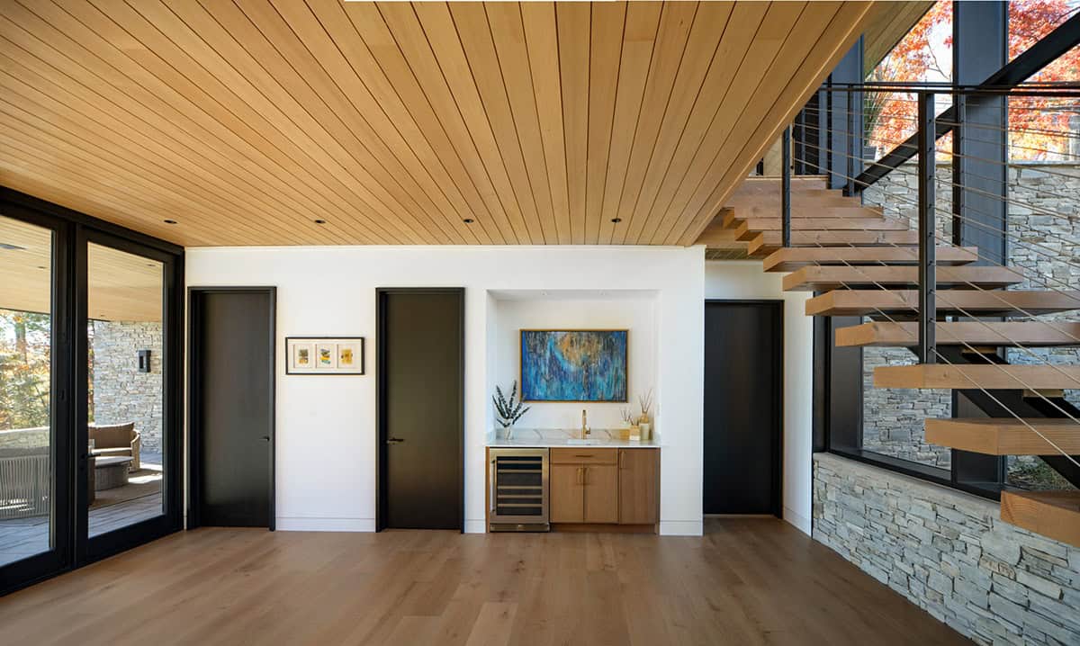 Wet bar nook with wine fridge beneath floating wood staircase