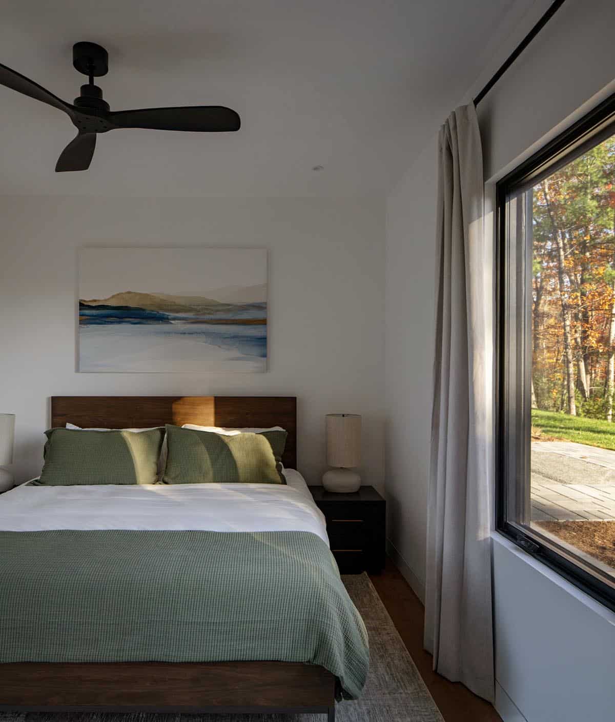 Bedroom with green bedding, dark wood headboard, and window view of yard