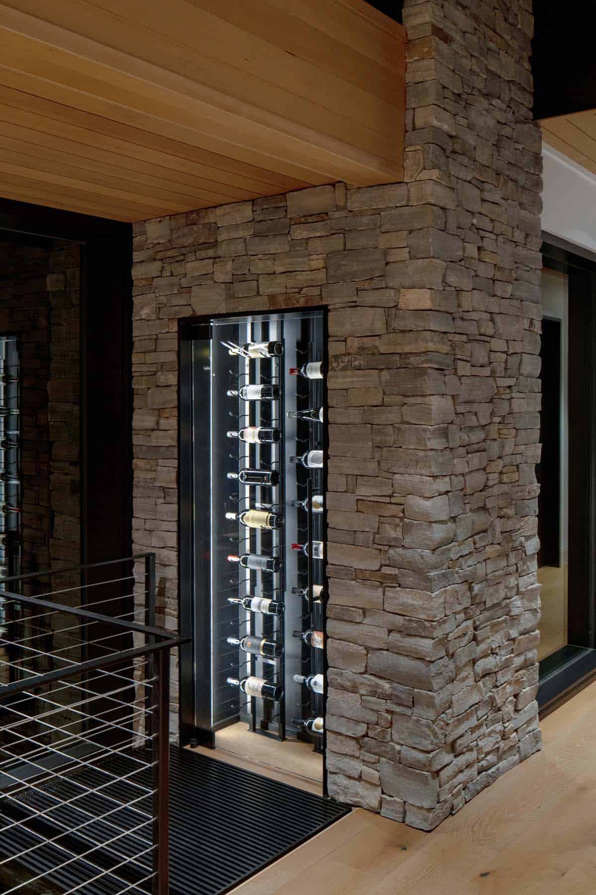Built-in glass-front wine cellar set into stacked stone column