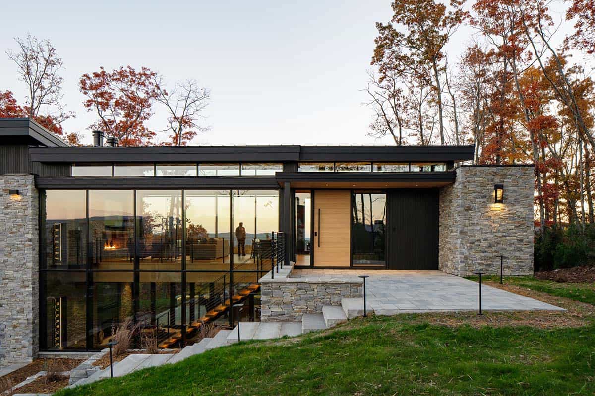 Modern home exterior with stacked stone entry and glass facade at sunset