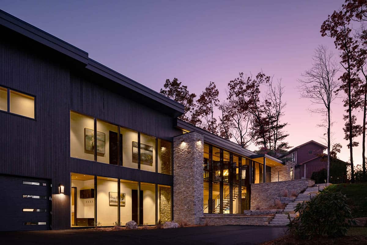 Exterior view of dark-clad modern home with stone accents at dusk