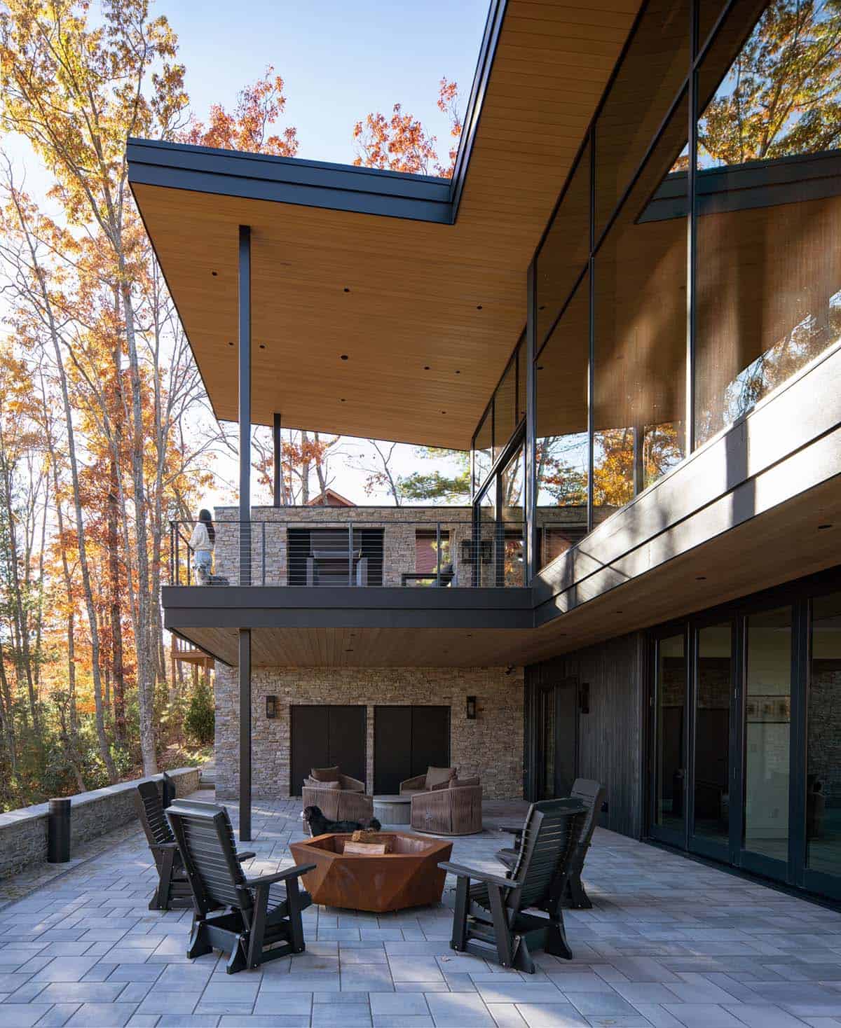 Cantilevered wood-ceilinged roof over stone patio with fire pit seating