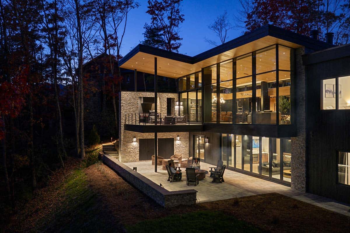 Nighttime exterior view of layered stone and glass home with illuminated interior